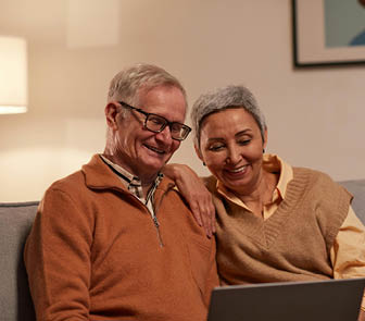 Older couple sitting together and looking at laptop