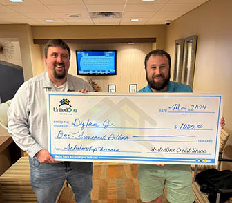 Image of two people holding a scholarship check Chief Marketing Officer Mike Farley presents a scholarship donation check to Dylan Johnston of Manitowoc